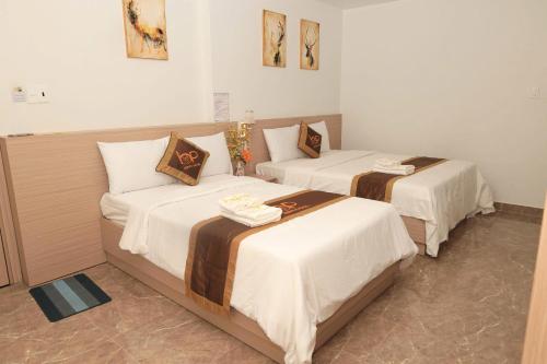 two beds in a hotel room with white sheets at Hugo Hotel in Phú Quốc