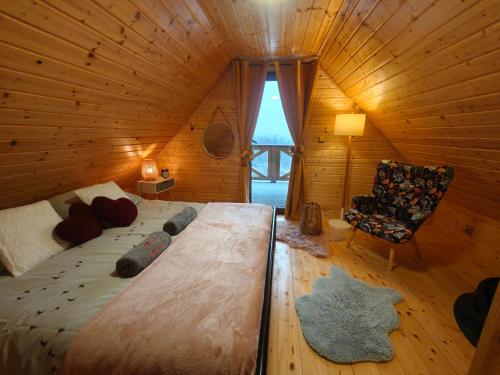 a bedroom in a log cabin with a bed and a chair at DOMKI KOLOROWE in Marciszów