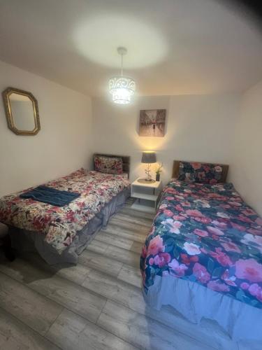 a bedroom with two beds and a table with a lamp at 2 Bedroom Apartment on suite bathroom, Southmead Bristol in Bristol