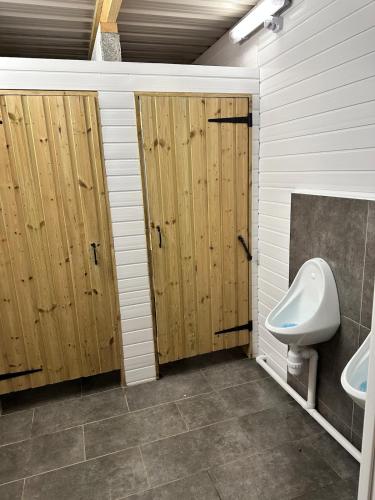 a bathroom with wooden doors and a toilet and a sink at Gypsy bow top caravan in Llangrannog