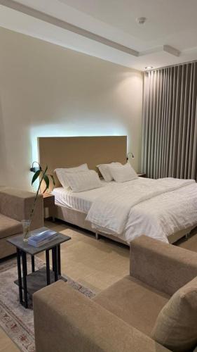a bedroom with a large bed and a table at وادي برزان للشقق المخدومة in Hail