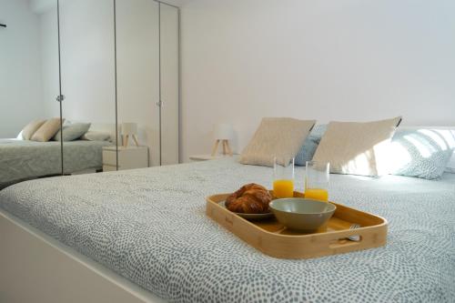 a tray with a bowl of food and drinks on a bed at Apartamento en primera línea de la playa in Arinaga