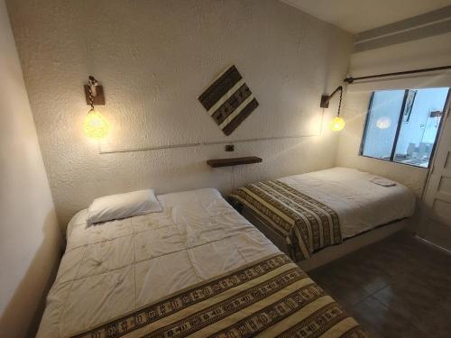 two beds in a small room with a window at Cabaña Sal y Piedra in Uyuni