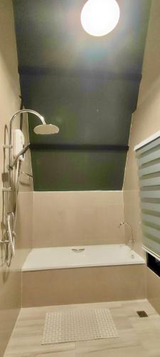 a bathroom with a bath tub with a light on the ceiling at บ้านไม้หอมชาเล่ต์ in Suan Phung