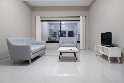 a living room with two chairs and a table and a tv at Milestone City Business Apartment - Secure Area - Fast WiFi Long Stay in Antananarivo