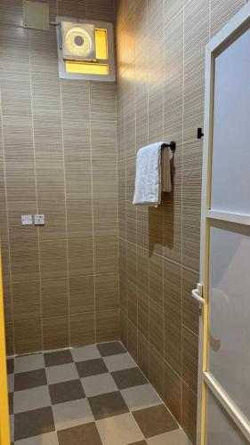 a bathroom with a shower with a checkered floor at وادي برزان للشقق المخدومة in Hail