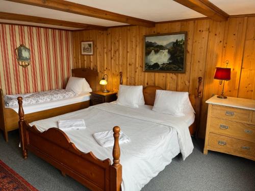 two beds in a room with wood paneled walls at Pension Gimmelwald in Gimmelwald