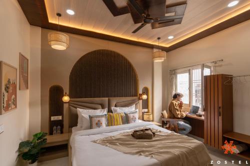 a bedroom with a bed and a person sitting at a desk at Zostel Varanasi in Varanasi