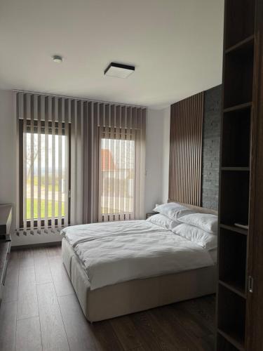 a bedroom with a large bed and two windows at BODU Vendégház in Balatonberény