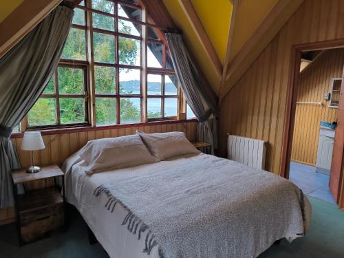 a bedroom with a bed in a room with windows at Casa de la bahia de Chiloé in Castro