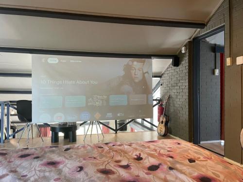 a projection screen in a room with a bed at heerlijk-huisje in Zandschel