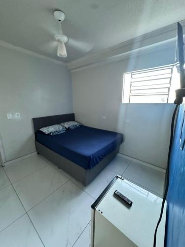 a small bedroom with a blue bed and a table at Pousada Amizade in Água Boa
