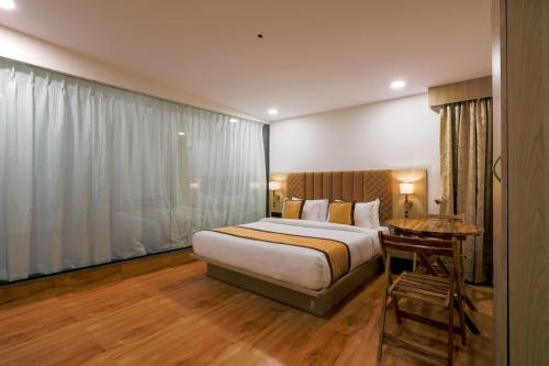 a bedroom with a bed and a table and a desk at De Classico Hotel Apartment in Mumbai