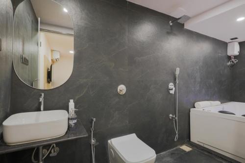 a bathroom with a sink and a mirror and a toilet at De Classico Hotel Apartment in Mumbai