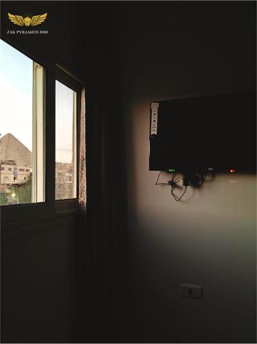 a flat screen tv in a room with a window at Zak Pyramids Inn in Cairo