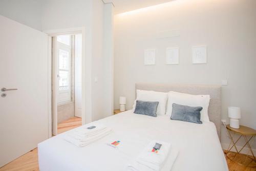 a white bedroom with a large white bed with two blue pillows at Liiiving in Porto - Aliados Stone Apartment in Porto