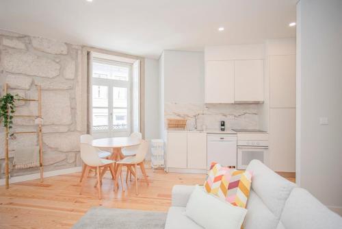 a white living room with a table and a kitchen at Liiiving in Porto - Aliados Stone Apartment in Porto