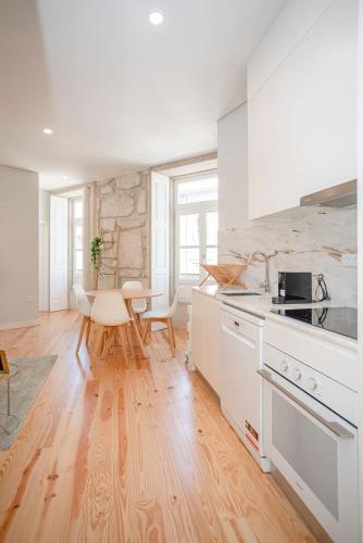 a kitchen with white cabinets and a wooden floor at Liiiving in Porto - Aliados Stone Apartment in Porto