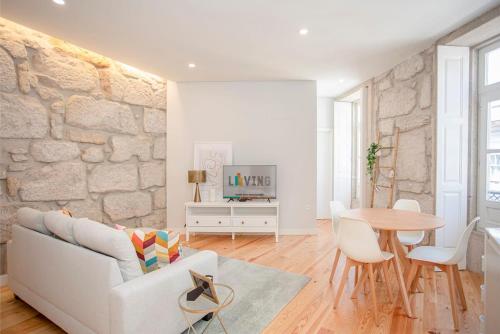 a living room with a white couch and a table at Liiiving in Porto - Aliados Stone Apartment in Porto