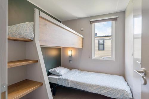 a small bedroom with a bunk bed and a window at Camping Papillon Bouillon - Vakantiehuis Premium Rustige Locatie in Bouillon
