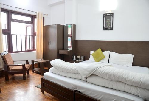 a bedroom with a large bed with white sheets at OS Hotel Pomra in Gangtok