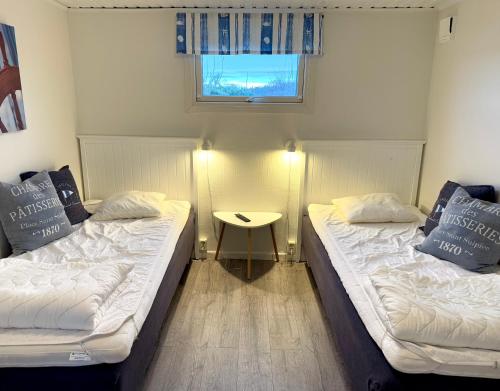 two beds in a room with a table and a window at GrebbestadFjorden stugor in Grebbestad