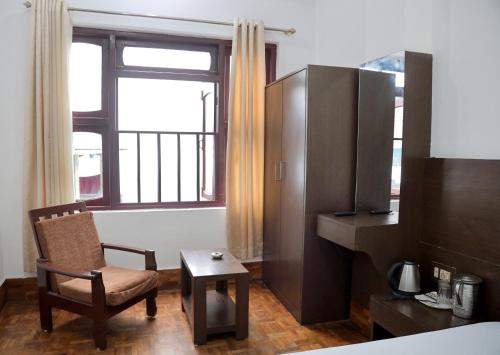 a room with a chair and a table and a window at OS Hotel Pomra in Gangtok