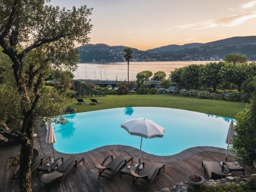 a swimming pool with chairs and an umbrella at Il Sole Di Ranco in Ranco