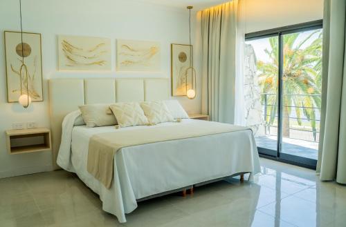 a white bedroom with a bed and a large window at Palmas de la Laguna by Posada Suiza in San Miguel del Monte