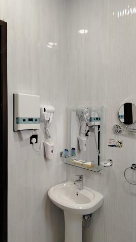 a white bathroom with a sink and a mirror at ﻣﺆﺳﺴﺔ ﺷﻘﻖ ﺍﻟﻘﺎﺭﺍﺕ ﺍﻟﺴﺒﻊ ﺍﻟﻤﺨﺪﻭﻣﺔ in Al Nairyah