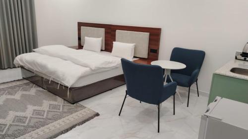 a bedroom with a bed and two chairs and a table at ﻣﺆﺳﺴﺔ ﺷﻘﻖ ﺍﻟﻘﺎﺭﺍﺕ ﺍﻟﺴﺒﻊ ﺍﻟﻤﺨﺪﻭﻣﺔ in Al Nairyah