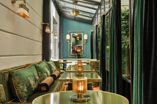 une rangée de tables dans une pièce avec un canapé dans l'établissement Lord Byron, à Paris