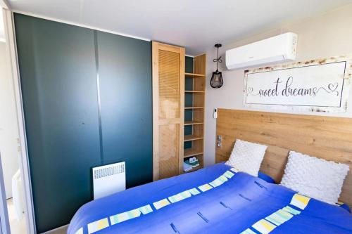 a bedroom with a blue bed with a wooden headboard at Camping Papillon Kinrooi - Vakantiehuis Familie 6P in Kinrooi
