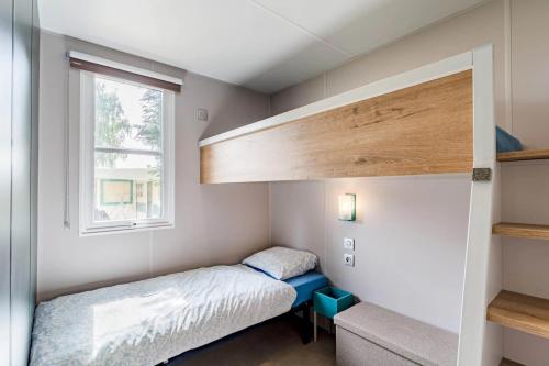 a small bedroom with a bed and a window at Camping Papillon Kinrooi - Vakantiehuis Familie 6P in Kinrooi