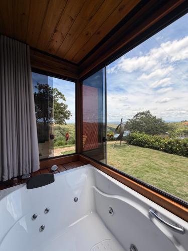 a bath tub in a room with a large window at Vale dos Ventos - Chalés e Hospedagem in Jaboticatubas