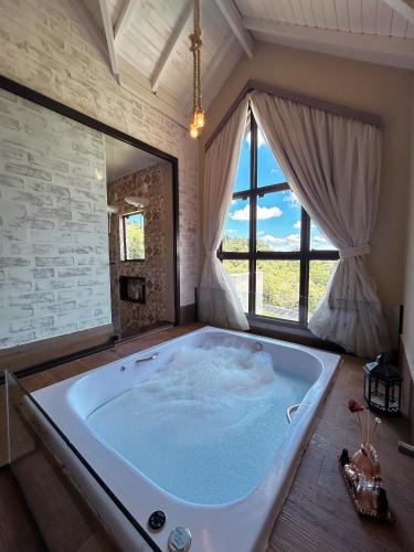 a large bath tub in a room with a window at Hotel Pousada Água Da Mina in Monte Sião