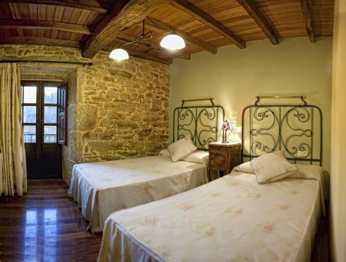a bedroom with two beds and a stone wall at Casa Gasamáns in Amés