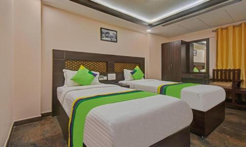 a bedroom with two beds with green and white sheets at Starlight Hotels Palm Tree Mylapore Ramakrishna Mutt Road chennai in Chennai