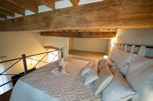 a large white bed in a room with wooden ceilings at La casina di Zora in Lorenzana