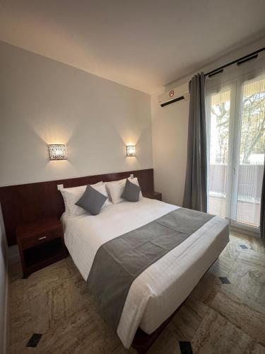 a bedroom with a large bed with two pillows at CITY PARC HOTEL - Proche Paris Nord & CDG Aéroport - Parc des Expositions in Aulnay-sous-Bois