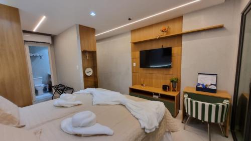 a bedroom with a bed and a desk and a television at Stúdio FRENTE MAR Centro de Convenções Salvador ArtStudio in Salvador
