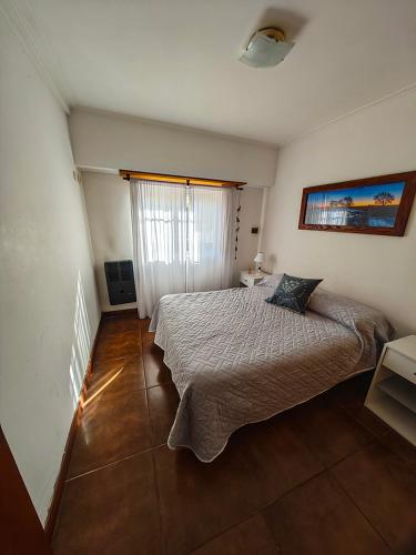 a bedroom with a bed and a large window at Dpto URQUIZA Olavarría in Olavarría