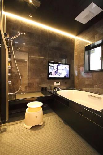 a bathroom with a tub and a toilet and a tv at Fuji Time traveler 新館 in Fujikawaguchiko