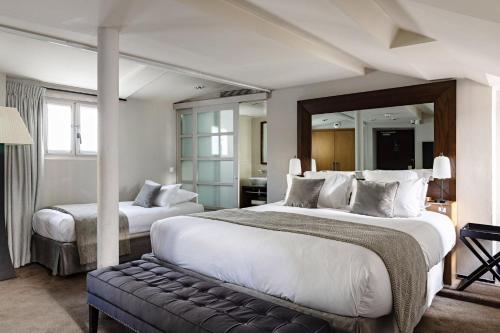 a hotel room with two beds and a mirror at Holiday Inn Paris Palais de l'Elysée by IHG in Paris