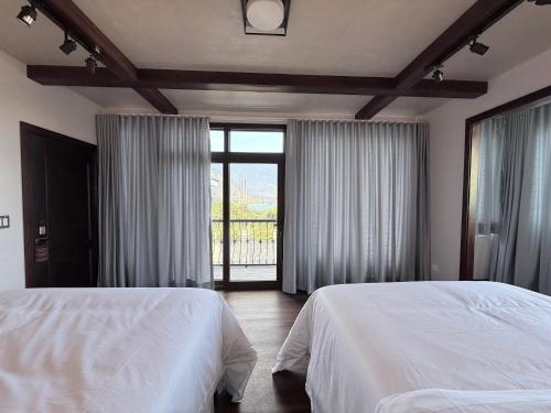 a bedroom with two beds and a large window at Casa Don Cristóbal Hotel y Restaurante Boutique in San Juan La Laguna