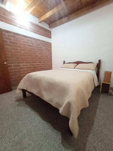 a large bed in a room with a brick wall at Casa Colmena Turismo Rural in Londres