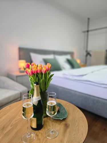 a table with two glasses of wine and flowers at Apartmány Baťovany in Partizánske