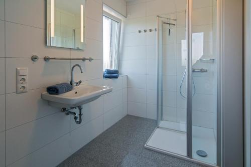 a white bathroom with a sink and a shower at Ferienhaus Atika in Bensersiel