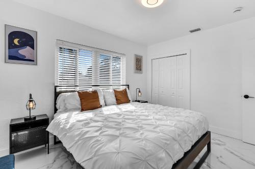 a white bedroom with a large bed and a window at Relax & Fun Hollywood Private Pool | Arcade Game in Hollywood