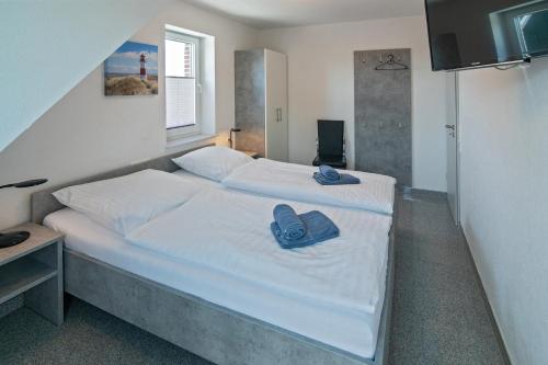a bedroom with a bed with a pair of shoes on it at Ferienhaus Empora in Bensersiel